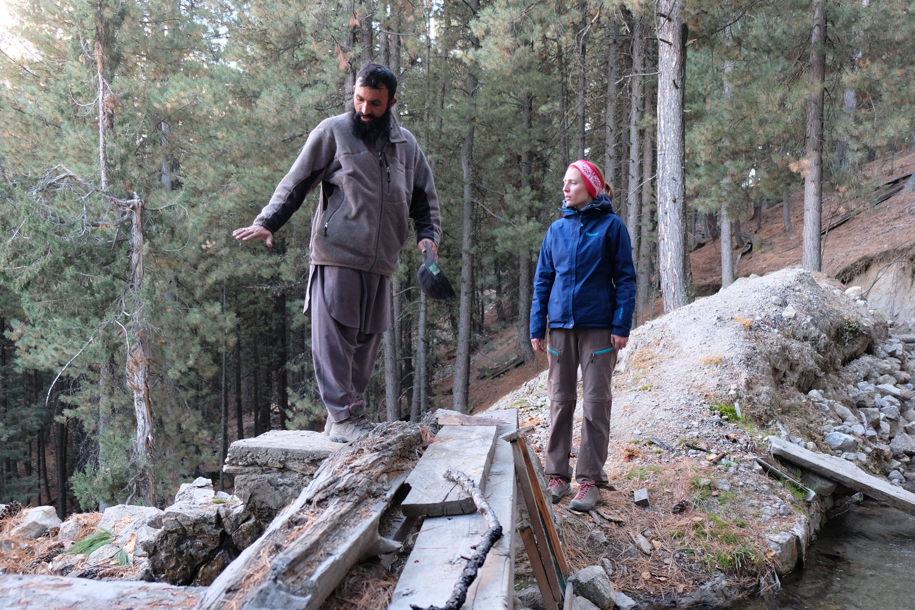 Leo steht im Wald neben einem Pakistaner, der ihr etwas erklärt.