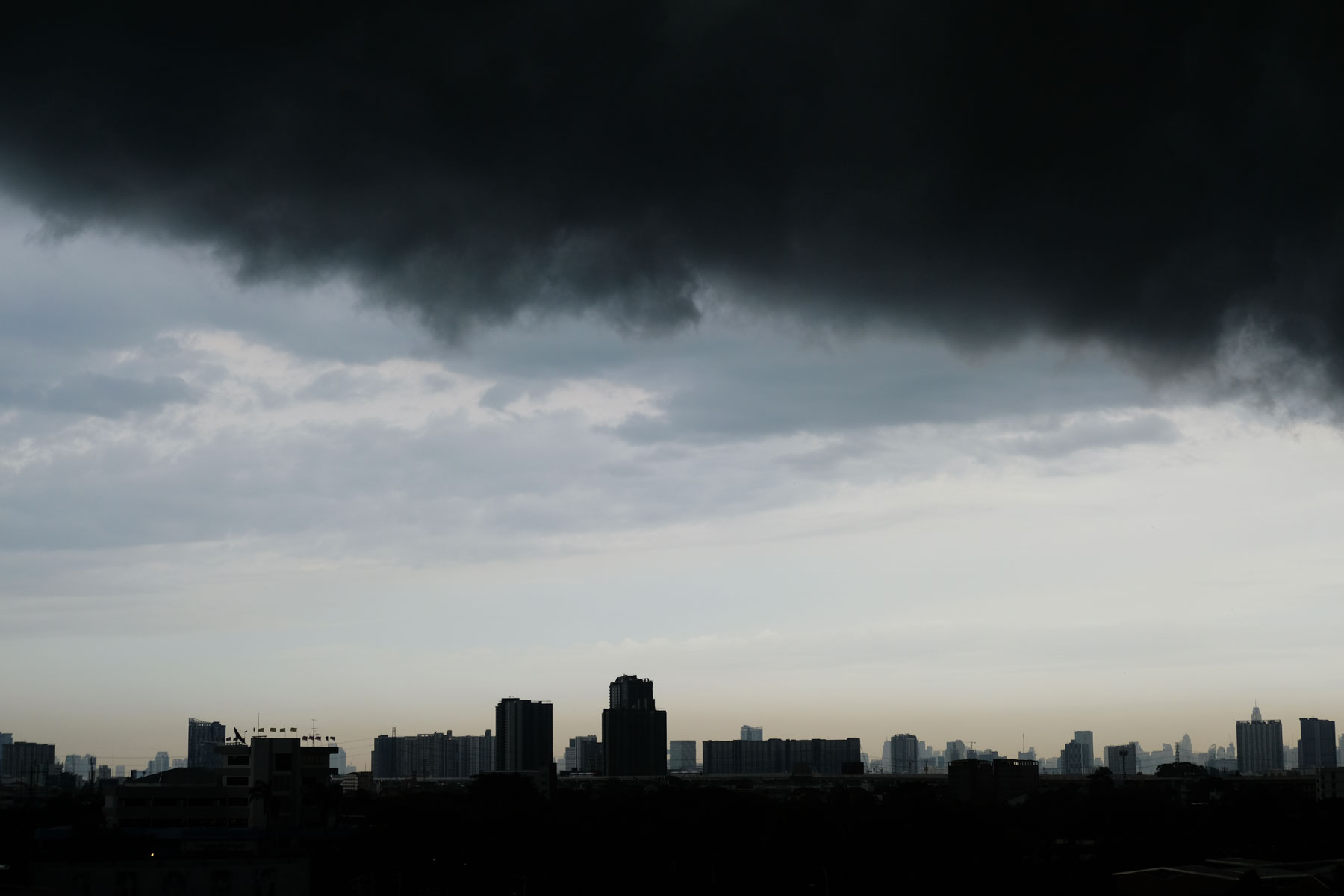 Eine schwarze Monsunwolke hängt bedrohlich über Bangkok.