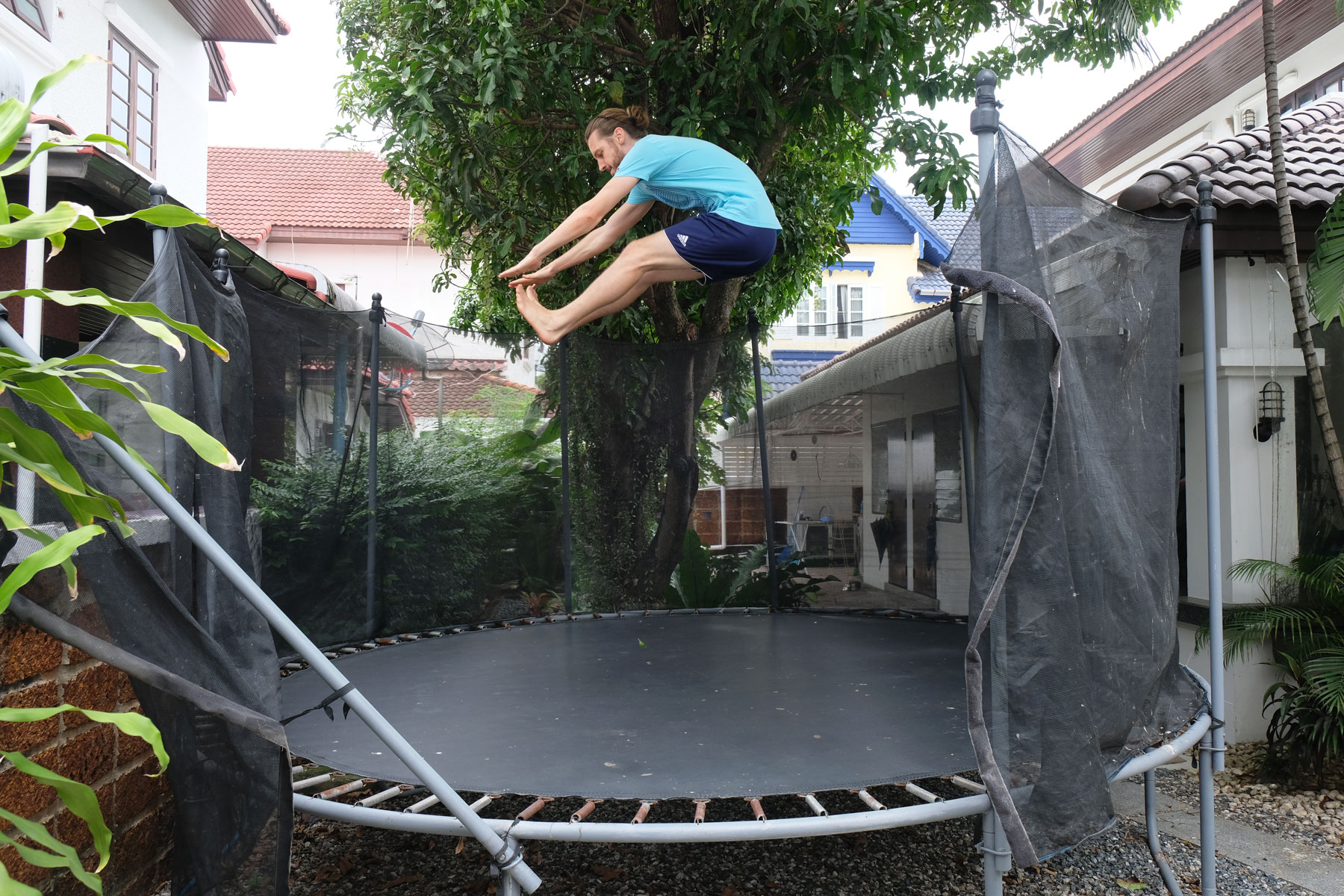 Sebastian hüpft auf dem großen Trampolin im Garten unseres Hauses in Bangkok